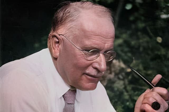 Foto de rosto do psicanalista Carl Jung de perfil com óculos, camisa branca, gravata areia fumando cachimbo. A foto ilustra o artigo "Carl Jung: O Inconsciente Coletivo e a Psicologia Analítica" do Homero Mônaco para o blog Online Psicanalista.