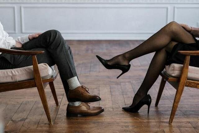 Foto onde aparecem duas cadeiras, uma em frente a outra. Em uma delas vemos as pernas de um homem, e na outra as fotos de pernas de uma mulher. A foto ilustra o artigo "Quais são as diferenças entre psicanalista e psicólogo?" escrito pelo psicanalista Homero Mônaco para o blog Online Psicanalista.