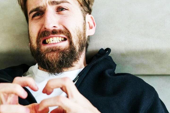 Foto de um homem deitado no divã de um psicanalista com cara de nervoso e irritado. A foto ilustra o artigo 7 Passos para Resolver Conflitos Internos de Relacionamento escrito no blog do psicanalista Homero Mônaco para ao site A Sessão de Terapia.