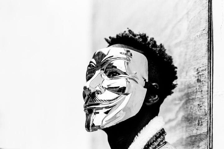 Foto em preto e branco do resto de um homem negro de perfil usando uma máscara tipo veneziana prateada. A foto ilustra o artigo O que são transtornos psicológicos? Quais são eles? Como tratá-los? escrito no blog do psicanalista Homero Mônaco para ao site Online Psicanalista.