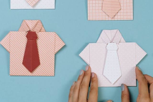 Foto de miniaturas de camisas com gravata e uma mão ajeitado uma delas para que fiquem no mesmo padrão. A foto ilustra o artigo Por que desconstruir os seus padrões comportamentais por meio da sua aceitação e da sua transformação escrito pelo psicanalista Homero Mônaco para o site Online Psicanalista.